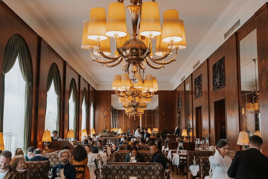 old-world dining room with shaded chandeliers, booths and wood panelled walls in best place to stay in Vienna
