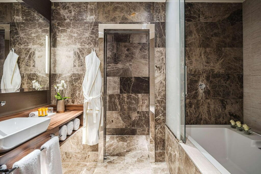 An exquisite bath tub with glass partition near the mirror