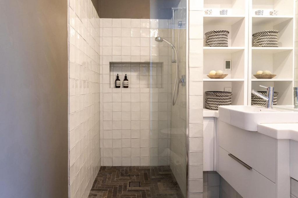 A white-tiled wall shower area near the sink