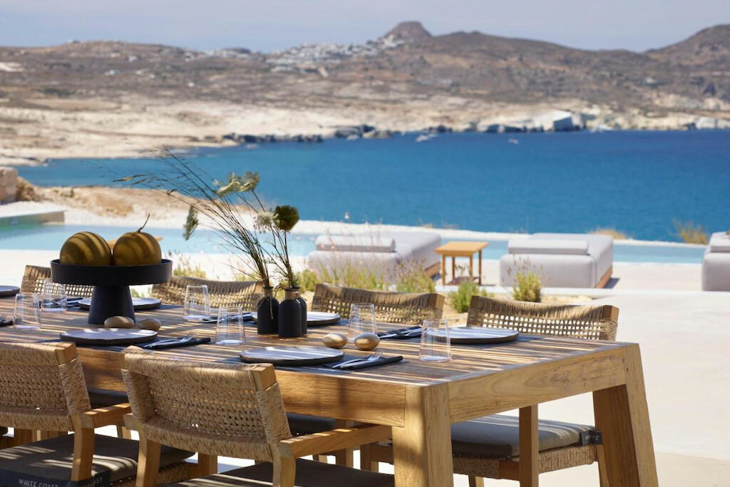 View of the outdoor dining table filled with condiments on top with an amazing view of the Aegean Sea at the background