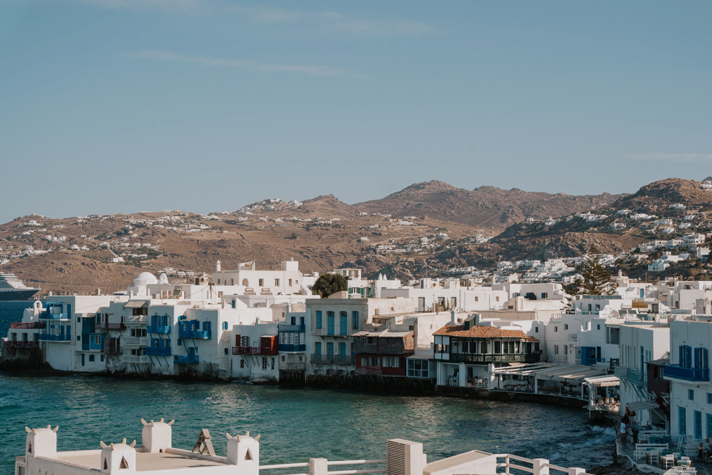 Overview of the Mykonos town with white buildings and mountains in the background
