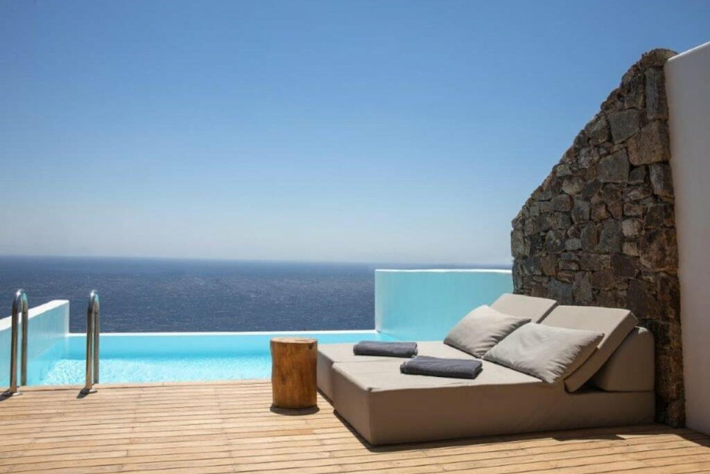 Pool mattresses with a wood-trunk table beside the private pool under the blue sky 