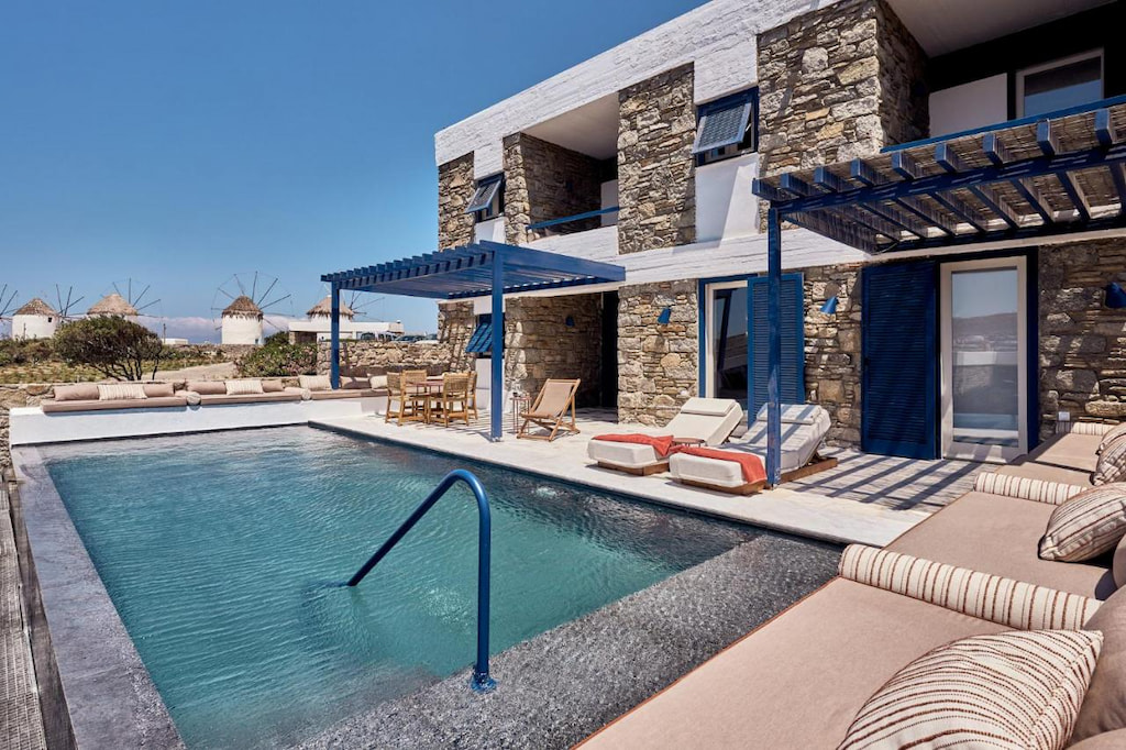 An outdoor pool surrounded by couch and benches in one of the luxury hotels in Mykonos 