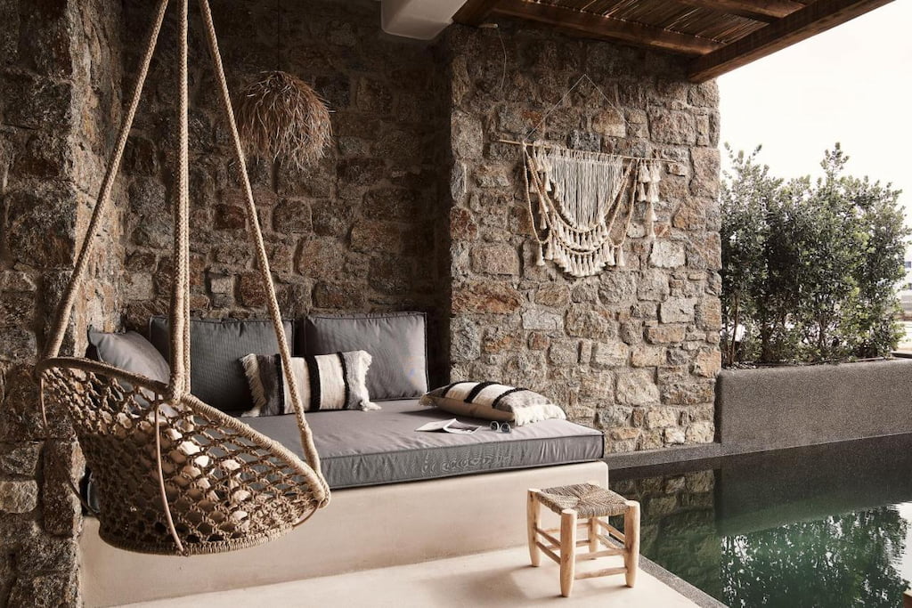 A swing chair in front of the gray couch beside the pool