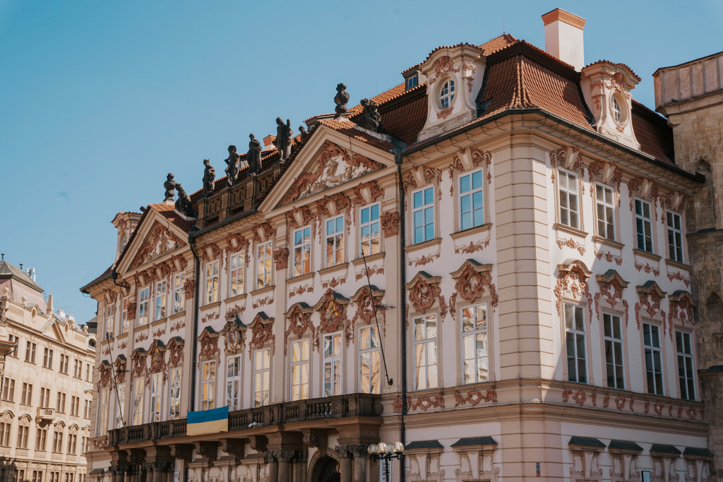 An ornate white and pink building with brown and gold accents in Prague's Old Town Square