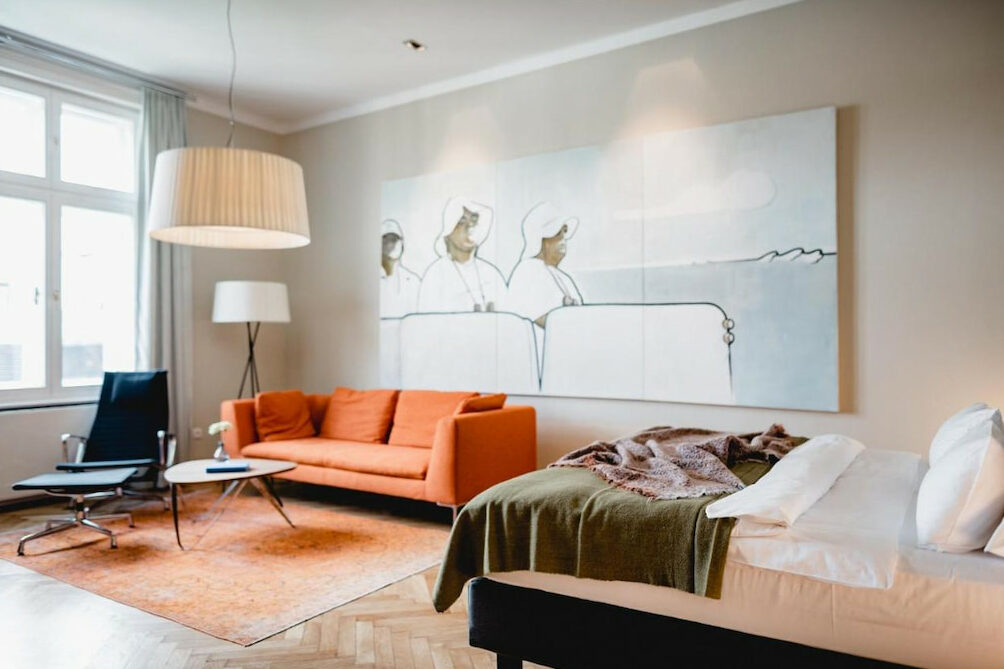 An orange couch near a cozy bed in one of the best boutique hotels in Vienna