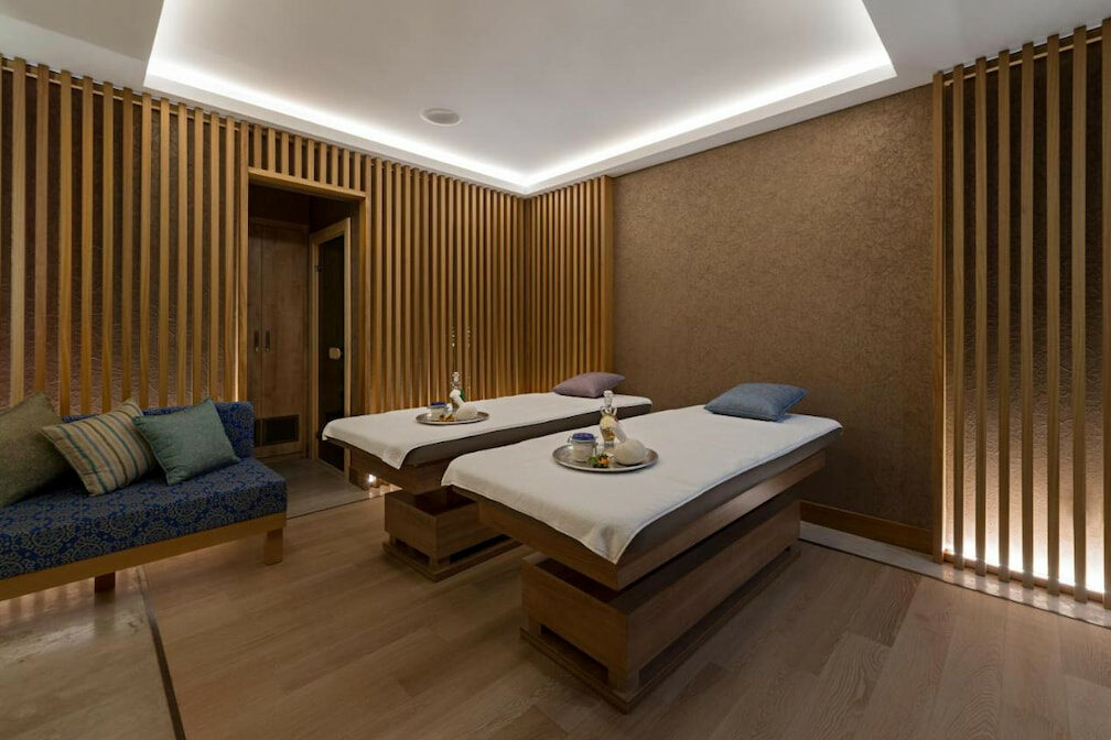 A private spa room with two massage beds near the blue couch