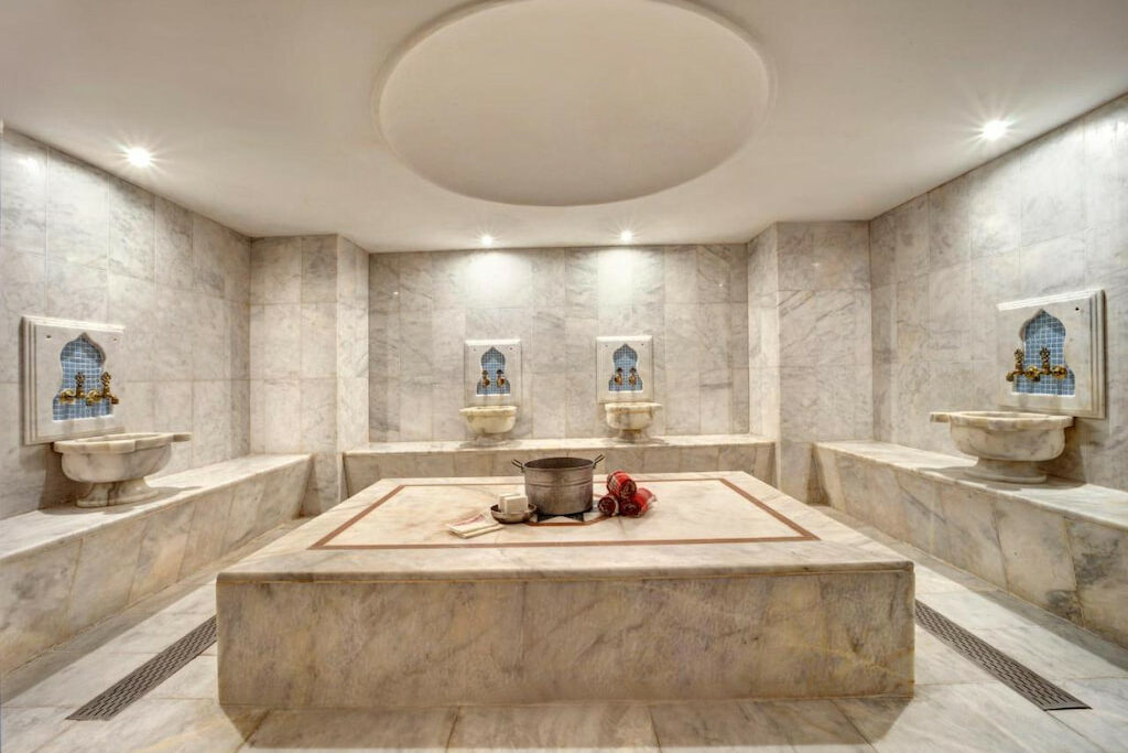 A unique spa room with sinks in each side of the room and a pot in the middle