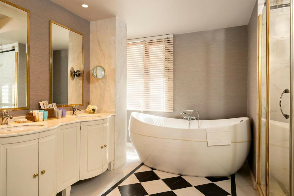 an elegant tub near the sink with gold mirrors on the side