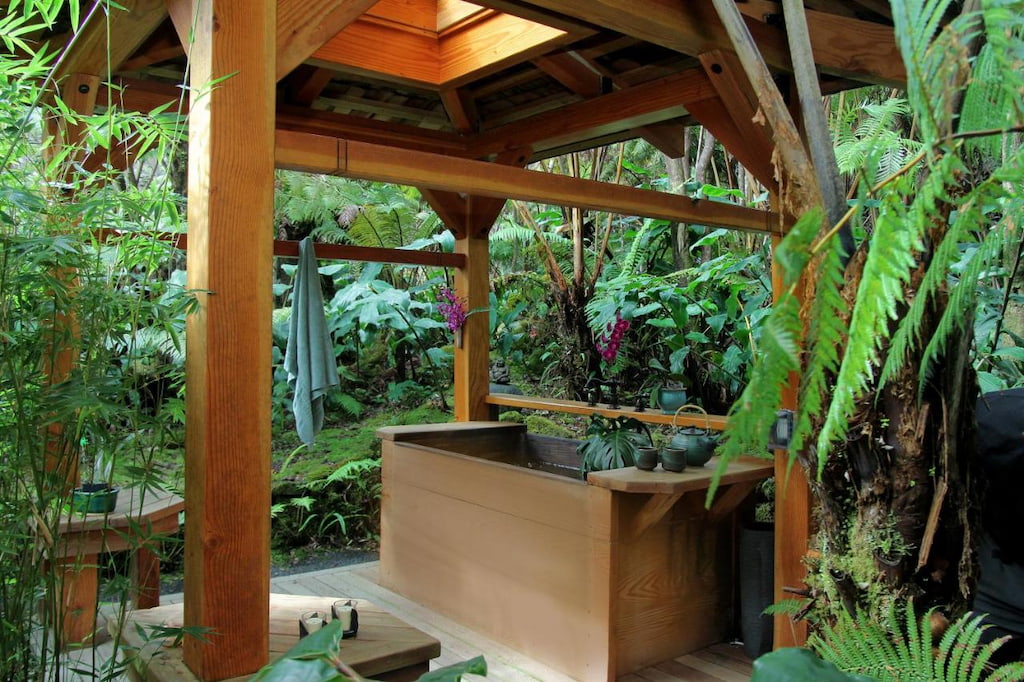 View of the  outdoor tub made of wood surrounded by lots of plants and trees