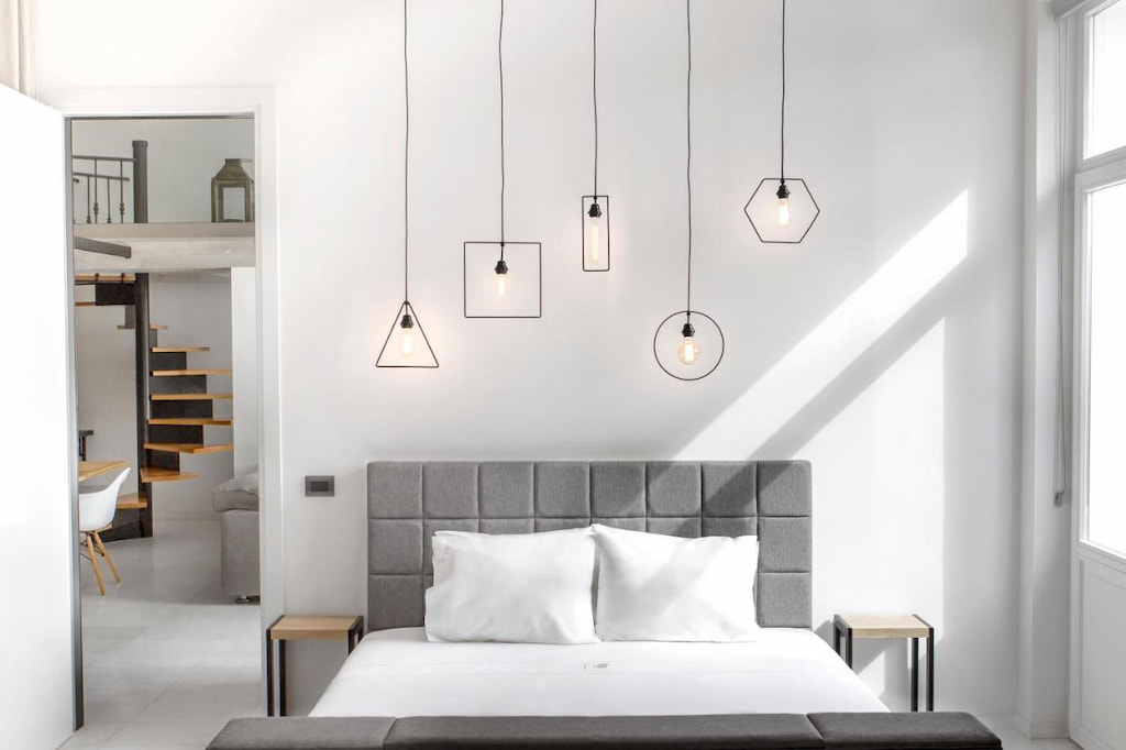 A cozy bed with gray headboard below the hanging lights
