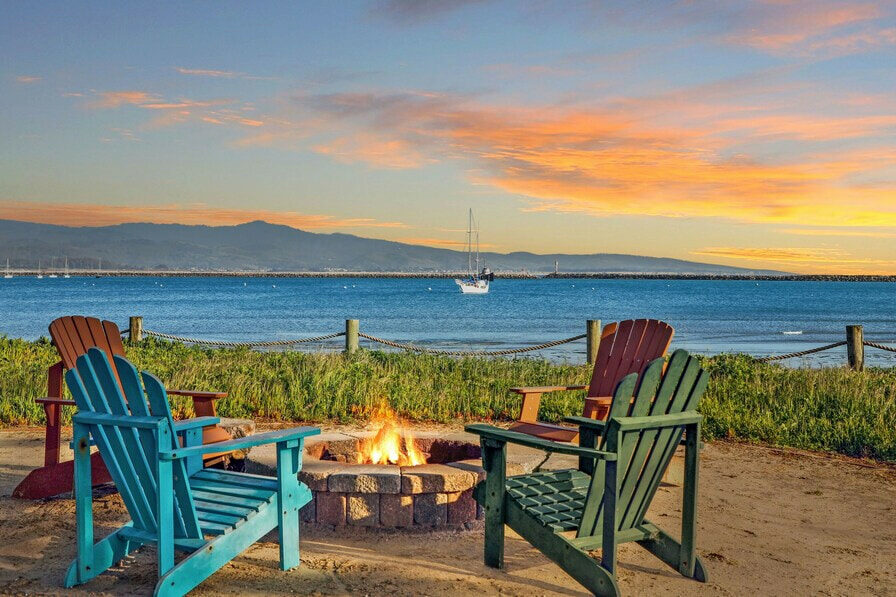 A sitting area outside the property with a fire pit and beautiful view of the beach.