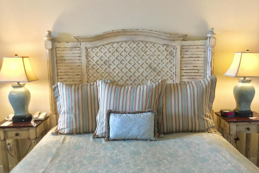 A vintage style headboard in one of the rooms of the unique hotel in Half Moon Bay with a couple of pillows and side table lamps.