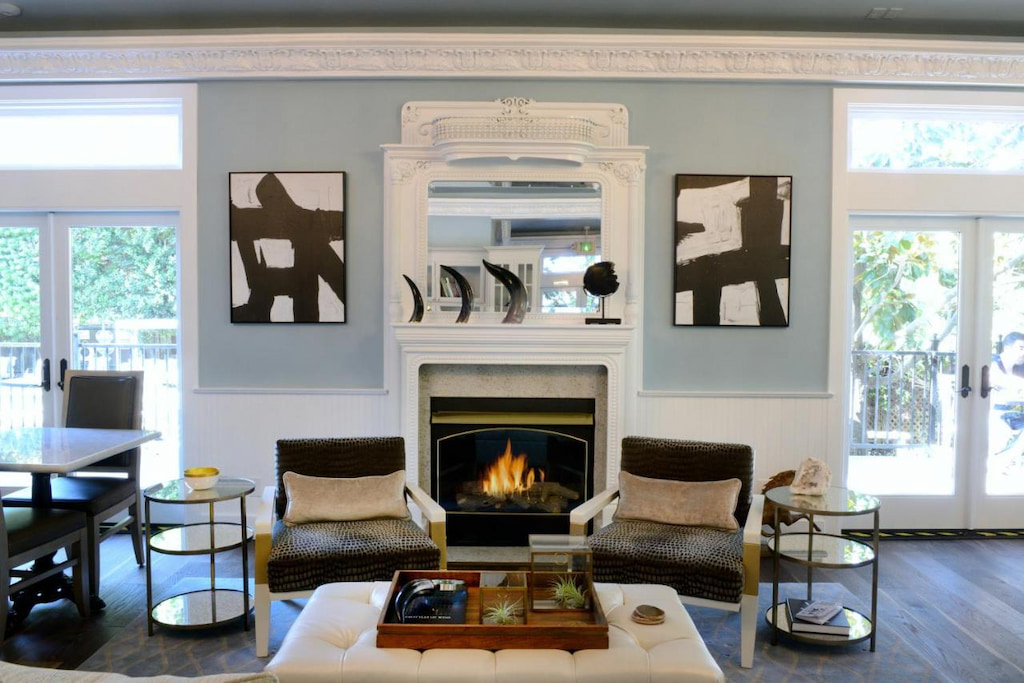 View of a modern style living room with accent chairs with animal skin cover near the fireplace below the mirror