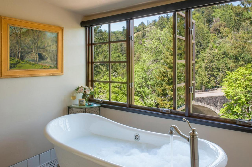 View of the bathroom area with a tub beside the window and view of the forest