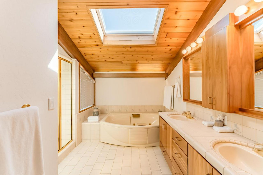 View of the luxury bathroom with a tub and long with an opening from its ceiling with the view of the sky
