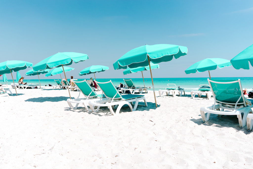 white sand beach with green umbrellas and sun loungers in Florida
