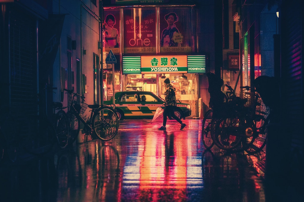 woman walking through at night through a city puns