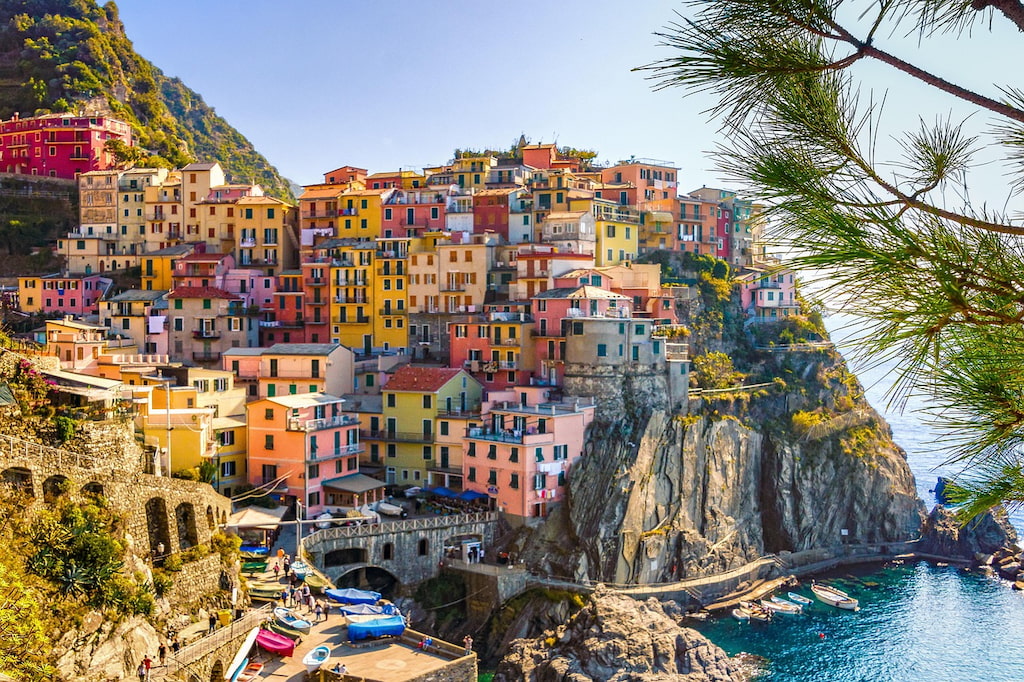 colorful homes on the side of a rock cliff with water below