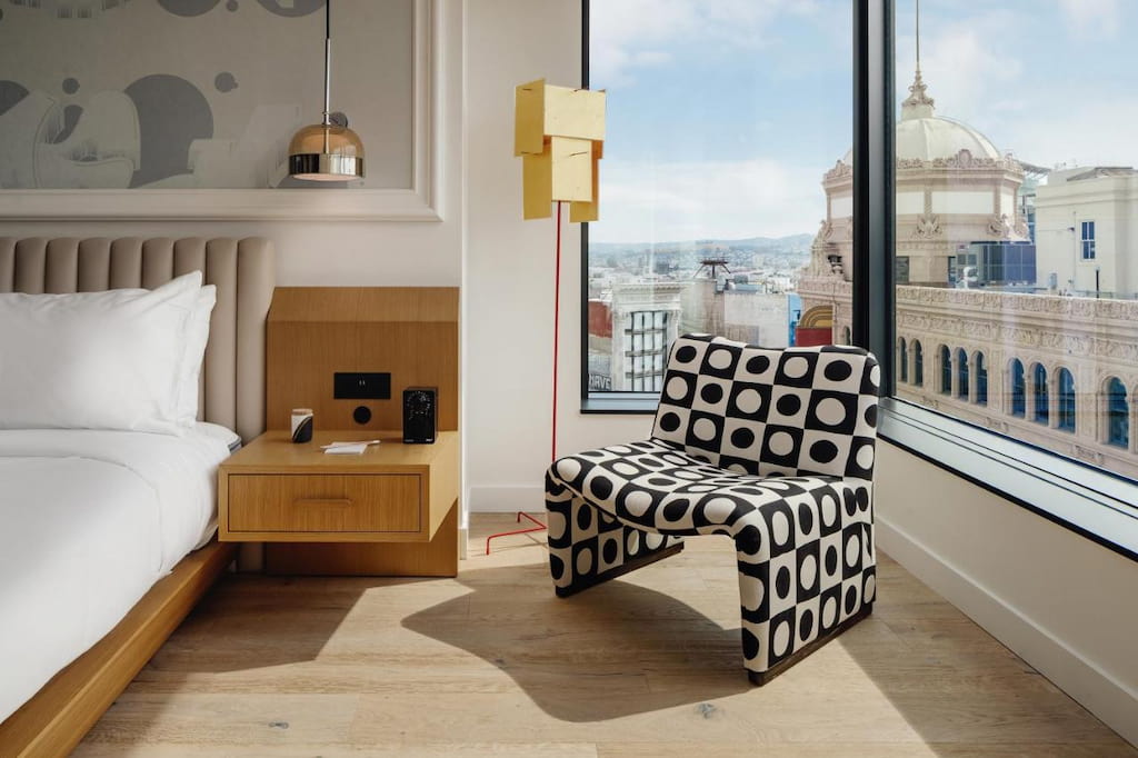 An accent chair with checkered design in black and white in the corner of the room near the window.