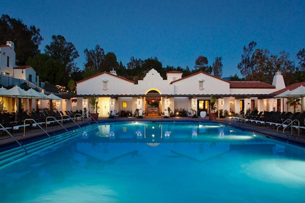 An outdoor swimming pool surrounded by padded pool benches at night in one of the Ojai hotels.