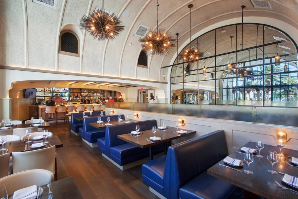 A sophisticated restaurant in Santa Barbara with blue chairs and chandeliers.