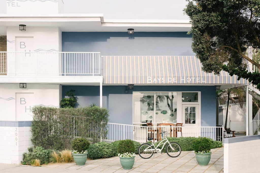 A simple hotel in Santa Monica's entrance with a bicycle parked outside.