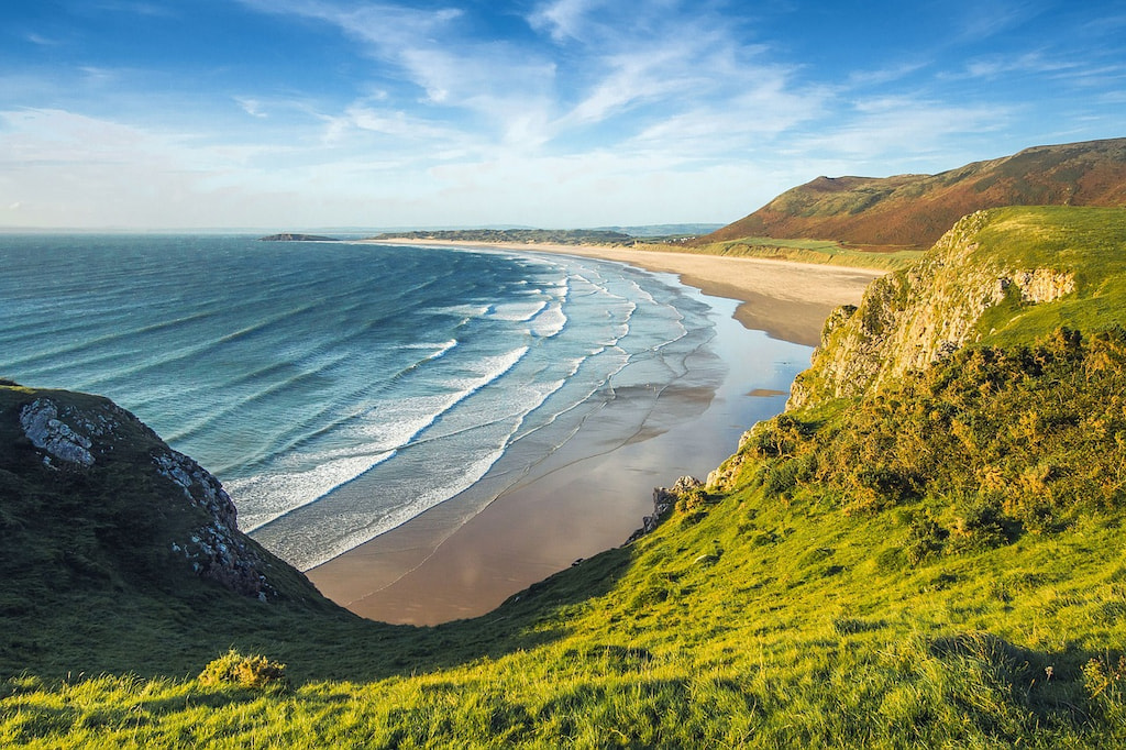 sunny coastline of England with green hills and blue water in summer one of the best times to visit England