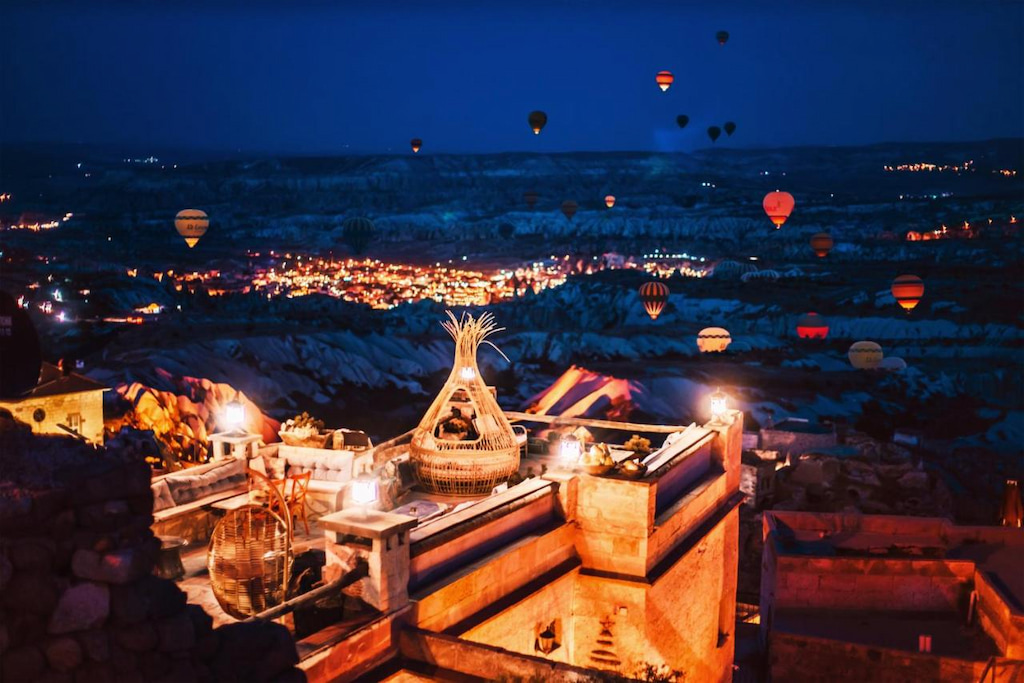 large wicker birds nest on the right and concrete seating on the left with Cappadocia and hot air balloons in the distance at the most photogenic hotel in Cappadocia to see balloons at night
