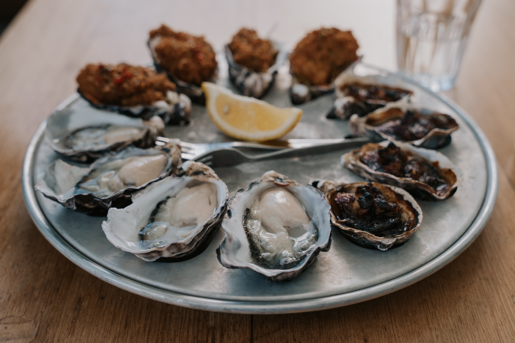 steel plate of various mixed open Bruny Island oysters on a wood table