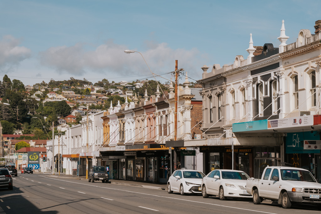 white Tasmania rental cars parallel parked along a main city road with historic buildings in Launceston