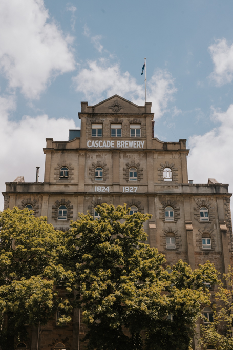 historic facade of Cascade Brewery in Tasmania with lush trees in front