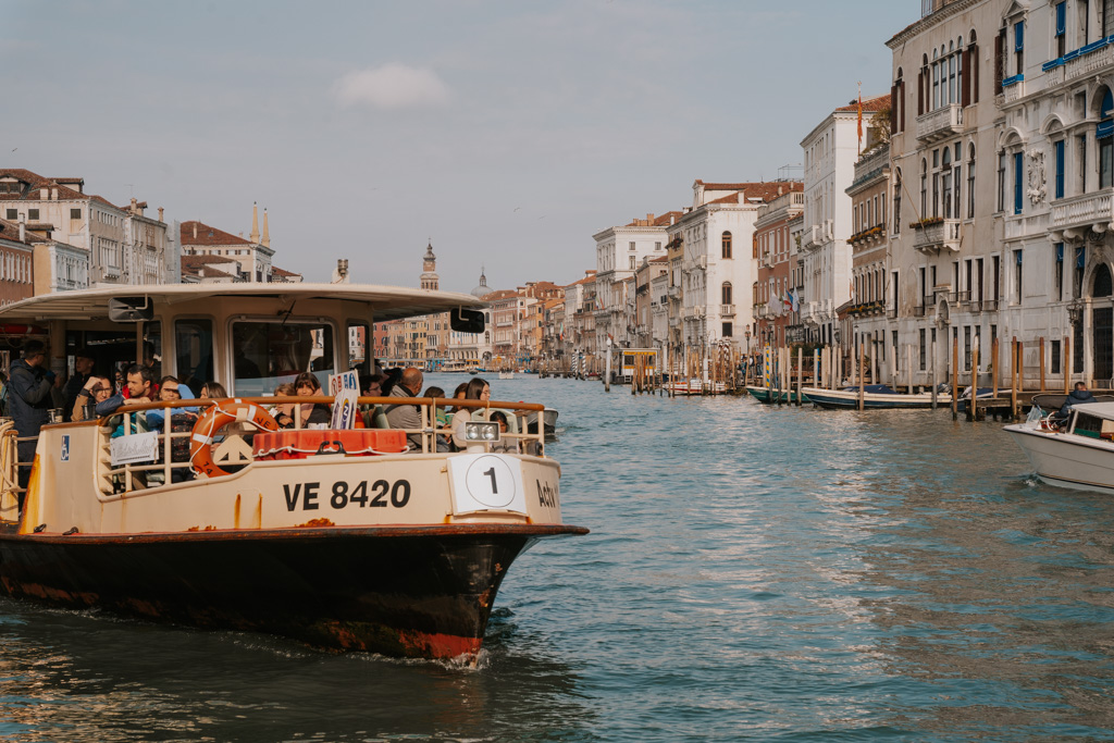 large white ferry boat with passengers and a sign that says #1 floats on the grand canal in Venice Italy