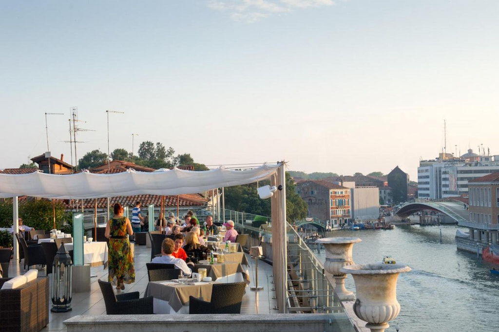 rooftop terrace and people dining overlooking the grand canal in the distance at this canal view hotel in Venice 