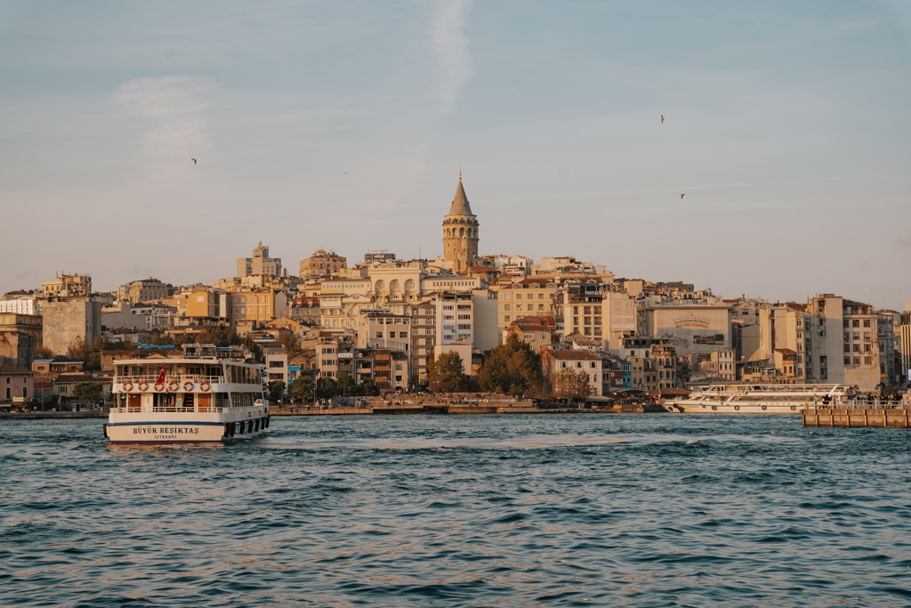 overlooking the district of Galata with the Galata tower piercing the skyline over the ocean with a ferry at dusk in Istanbul Turkey