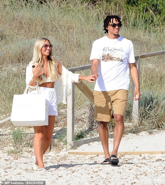 Having fun? The Liverpool FC star put on a cosy display with the blonde beauty as they strolled along the beach together before boarding a boat