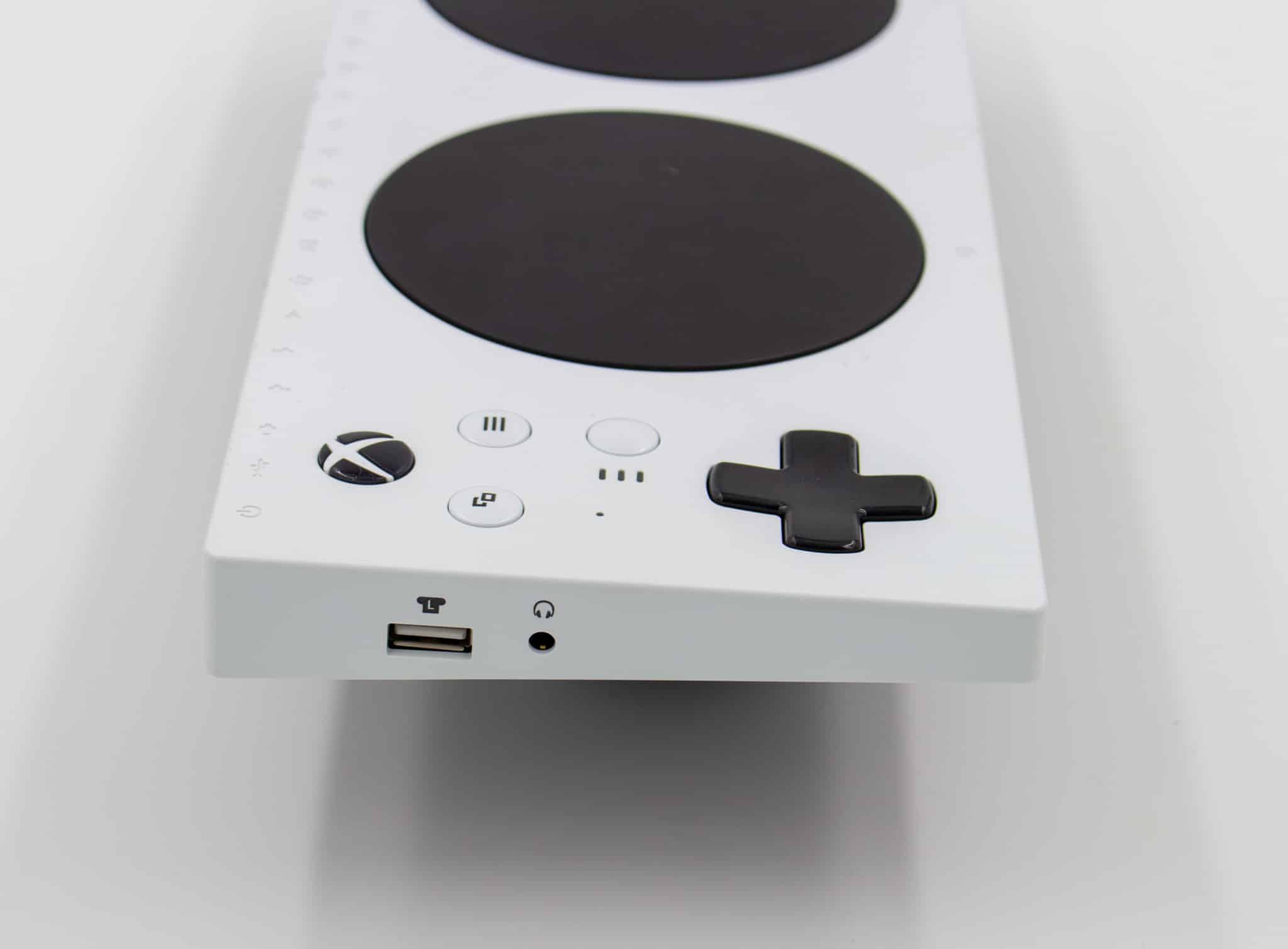 The side of an Xbox Adaptive Controller. There is a USB port and an audio port with icons above them.