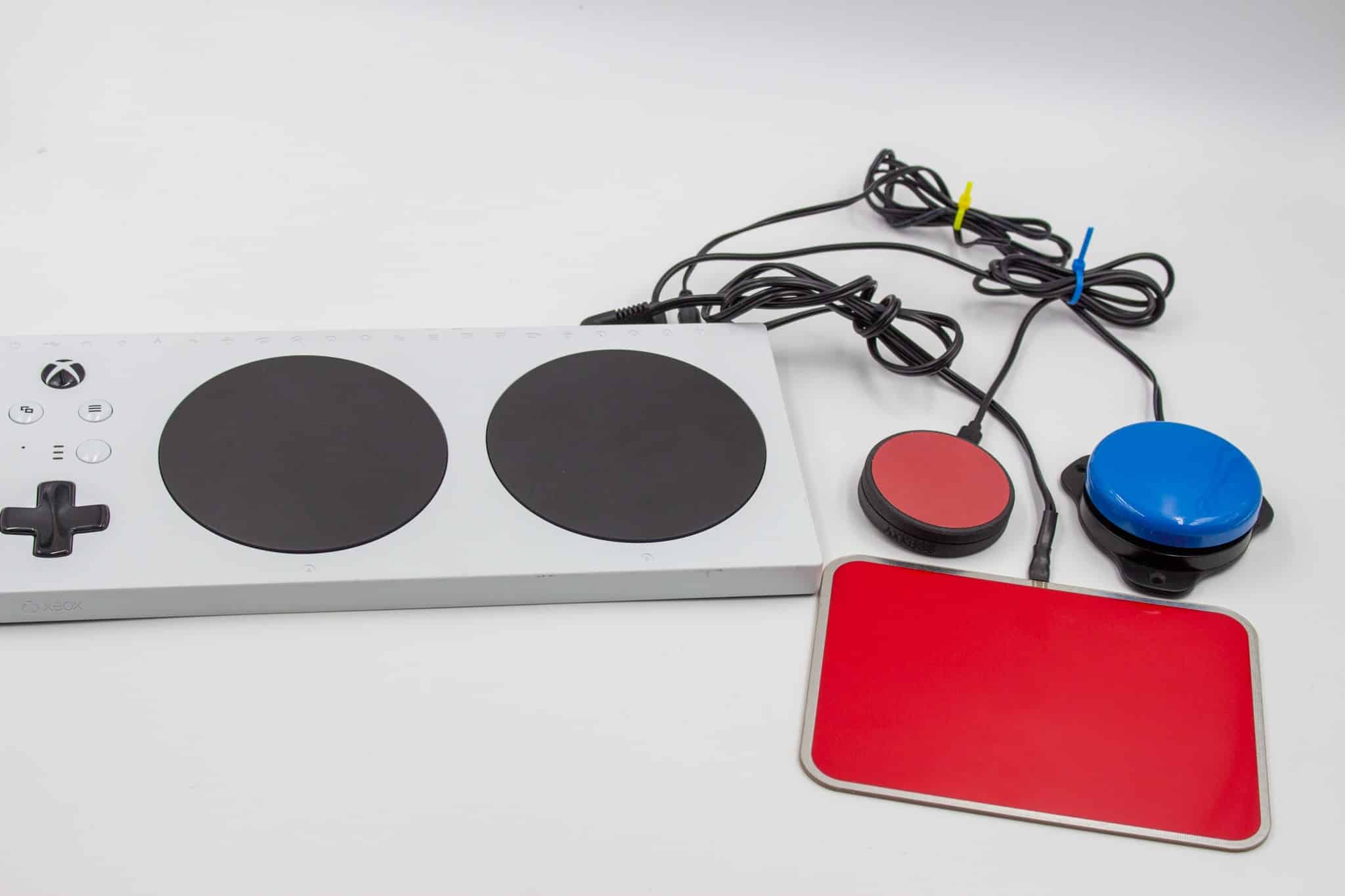 A red and blue button placed behind a red touchpad. They are all connected to an Xbox Adaptive Controller.