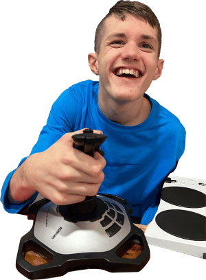 A young boy, 15 years old smiling using a joystick and an xbox adaptive controller in the background