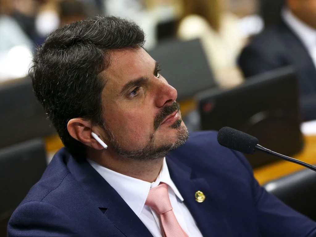 O senador Marcos do Val durante reunião da Comissão de Constituição e Justiça do Senado para análise de projetos de decretos legislativos que sustam o decreto presidencial que dispõe sobre uso, porte de armas no país; do Val é um homem branco com cabelos e bigode castanhos, ele veste um blazer azul com camisa branca e gravata rosa