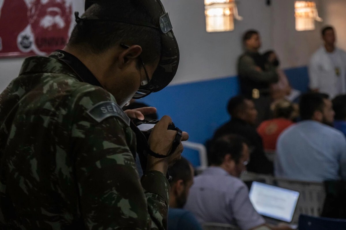 Soldado mexe em câmera em sala de imprensa.