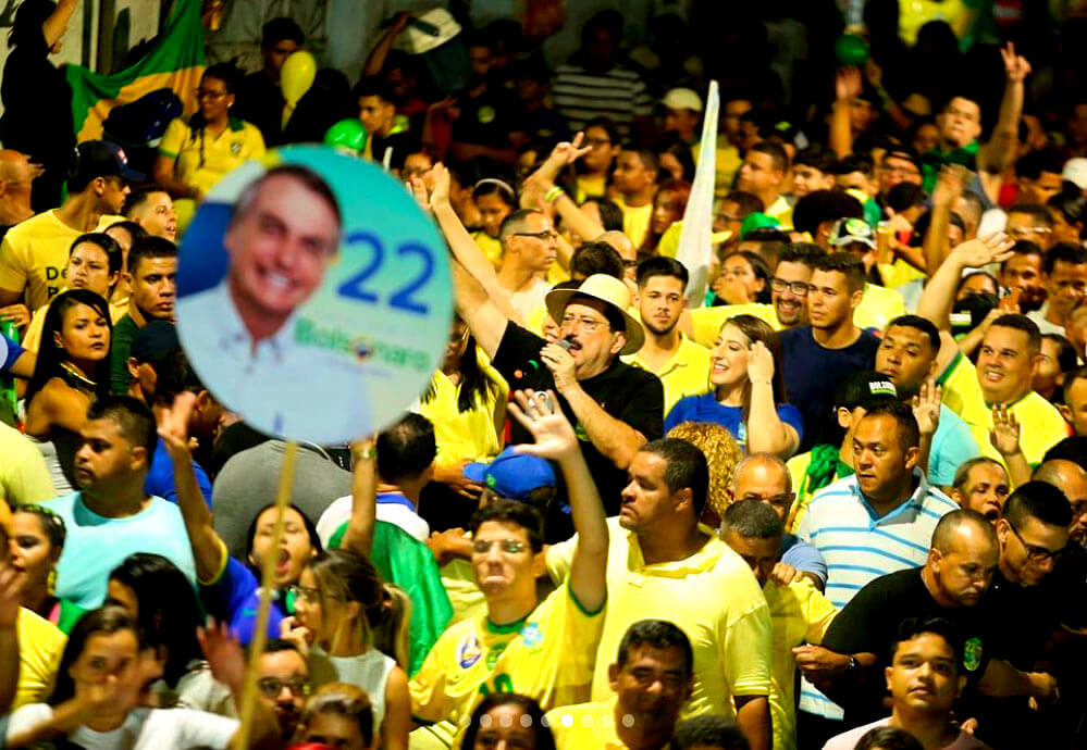 Na imagem ao centro, o prefeito Gilberto Gonçalves (PP), de Rio Largo. Gilberto Gonçalves é um homem branco com cabelos e olhos pretos e bigode, ele usa chapéu e fala ao microfone. Ao redor de Gilberto estão apoiadores do então candidato à presidência Jair Bolsonaro.