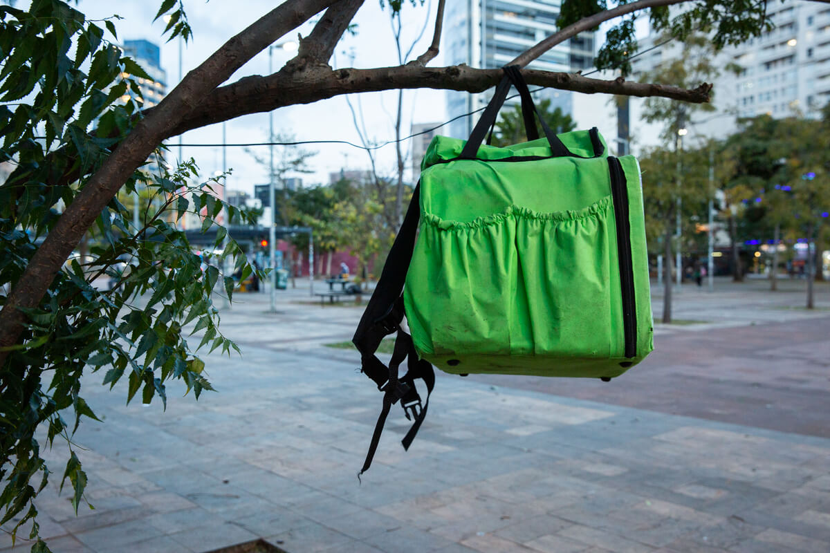 Mochila de entregador de aplicativo pendurada em galho