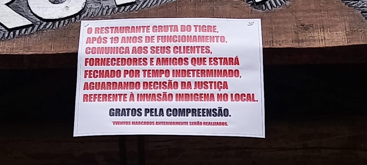 Cartaz de aviso de restaurante acusando invasão invasão indígena no local.