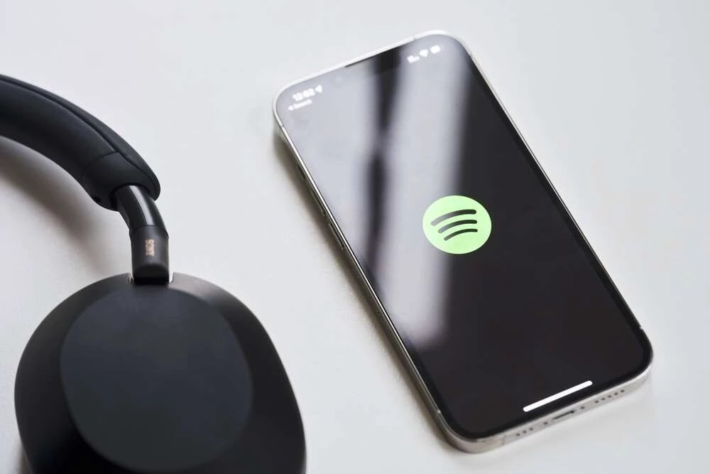 Fone de ouvido e celular ligado no aplicativo de músicas Spotify