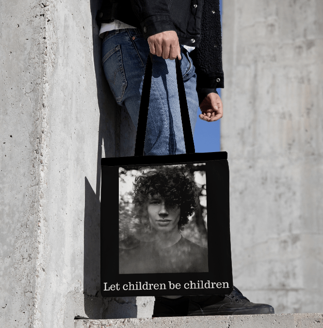 Černá plátěná taška s uměleckou fotografií od Ivy Haj, zobrazující českého aktivistu Daniela Blacka. Pod snímkem je text "Let children be children". Stylová a odolná taška na podporu iniciativy BASED INITIATIVE Z. S.