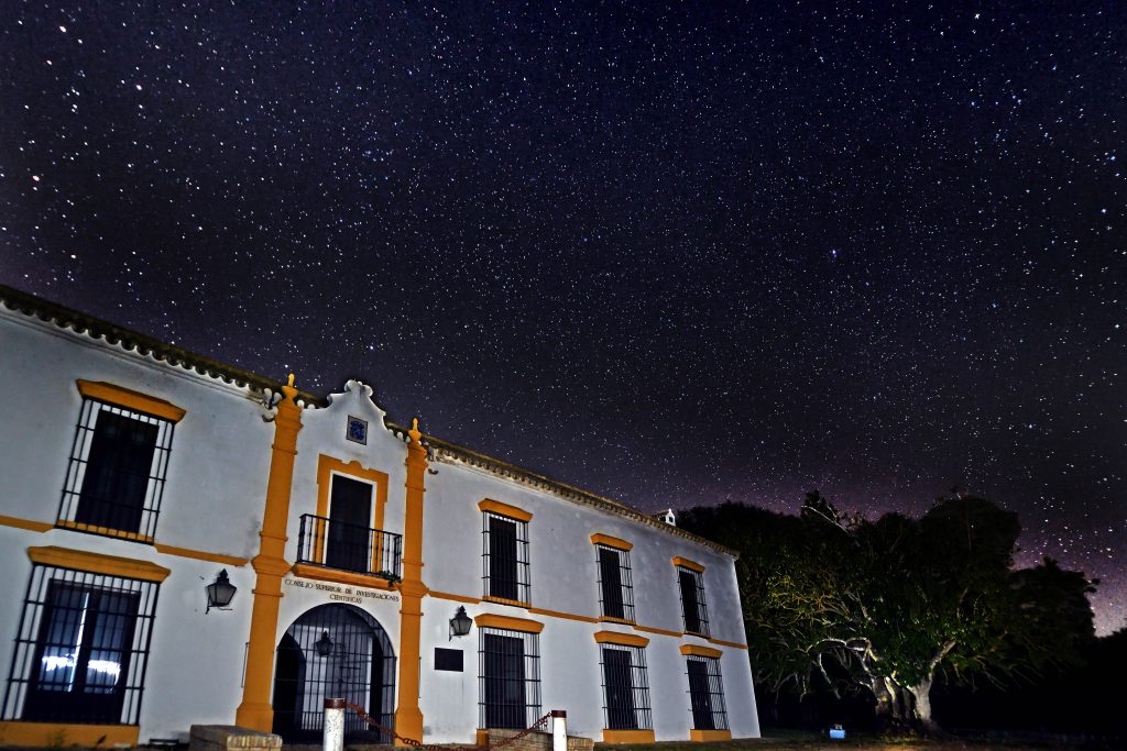 A building with a sign that says "Consejo superior de investigaciones científicas" against a background of starry sky.