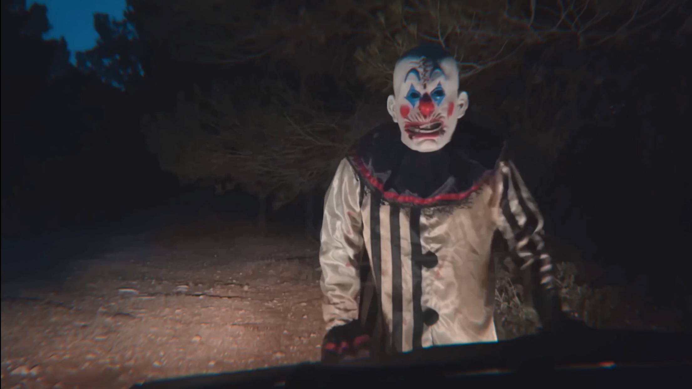 The Thing (Juan Ramos), a clown in blakc and white, is caught in the headlights of a car