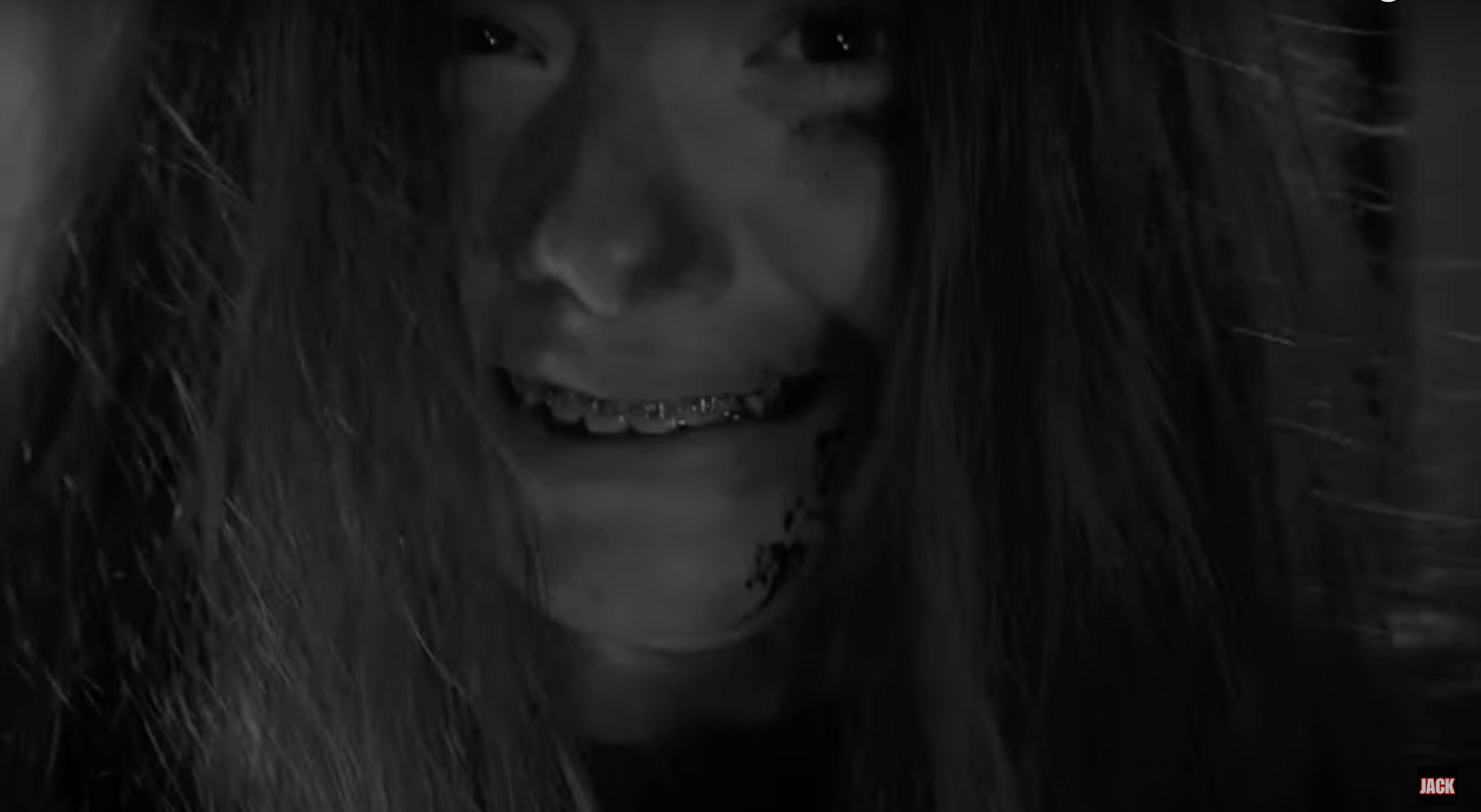 A black and white extreme close up of a crying girl with braces