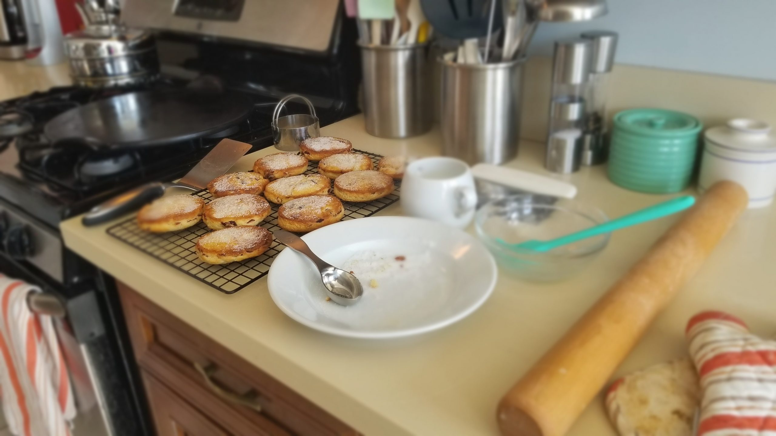 angle of Welsh cakes on a cooling rack with a bowl of sugar